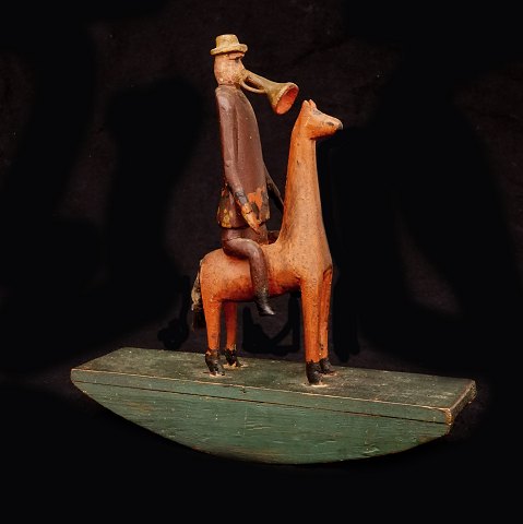 Trompetespielender Mann auf einem Pferd. Holz. 
Schweden um 1880. H: 25,5cm. L: 25cm