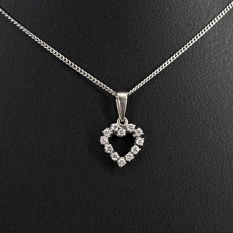 A 14k white gold necklace set with a heart shaped diamond pendant