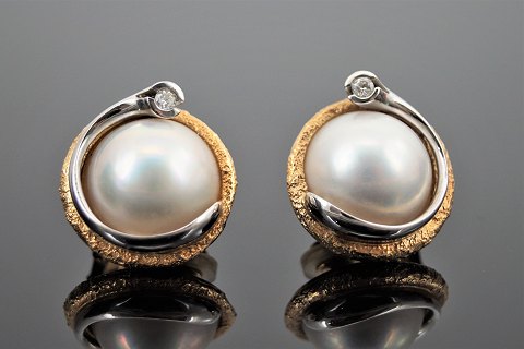 Ole Lynggaard; A pair of earclips of 14k gold and white gold with a diamond and 
a mabé pearl