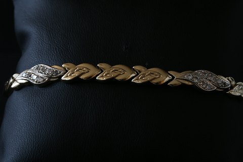 Elegant og stilet guldarmbånd i 14 karat guld, med kasselås og indlagte klare 
sten.