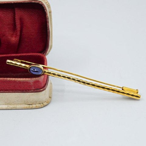 Brooch in 14k gold set with a sapphire