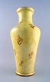 Stor Sevres vase i porcelæn med gul glasur.
Dekoreret med blomster i guld.
