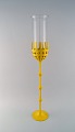 Bjørn Wiinblad (1918-2006). Large Hurricane candlestick in yellow lacquered 
metal with blue tinted glass. 1970s / 80s.

