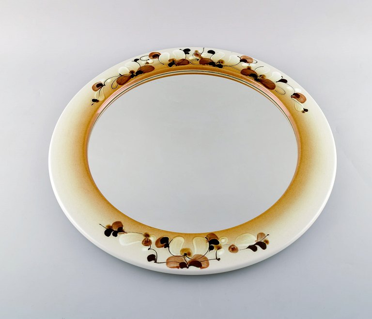 Ellen Malmer for Royal Copenhagen. Large round mirror in glazed faience 
decorated with flowers on the frame. Dated 1965.